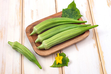 green okra pods on cutting board with a knife. on white table.