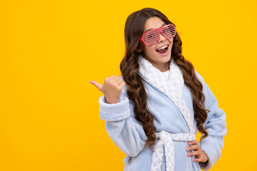 Portrait of teenage girl in funny glasses and pajama or home bathrobe feeling fun isolated on...