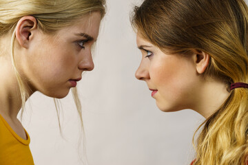 Two girls looking serious at each other.