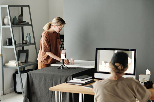 Young blond woman creating composition on table while preparing for shooting of new commercial about cosmetic products