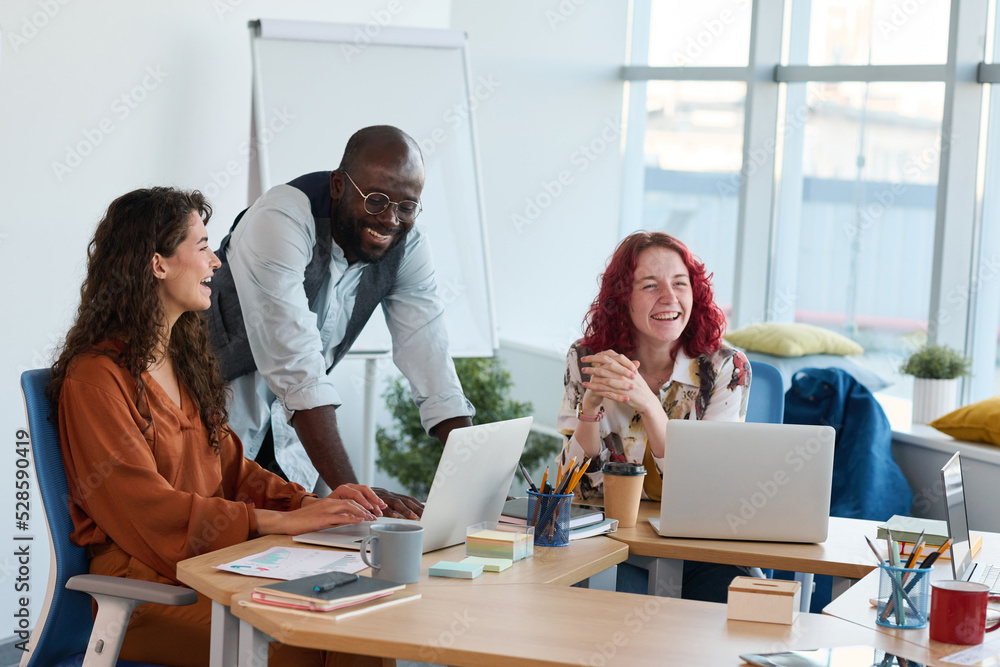 Aufkleber three young multicultural employees laughing at working meeting in office during discussion of new i
