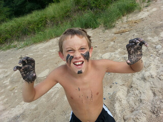 Boy playing on the beach with  rare black magnetic sand painted on his face, Lake Michigan - obrazy, fototapety, plakaty