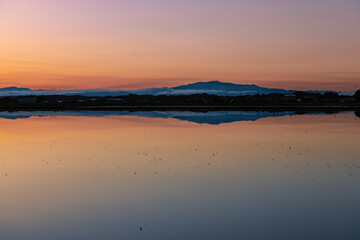 日本　栗駒山と夕焼けで水鏡の春の田園風景