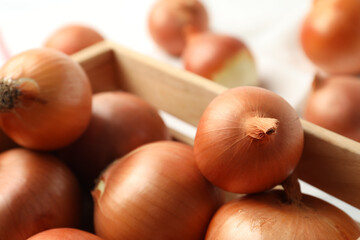 Ripe yellow onion bulbs in wooden crate, closeup