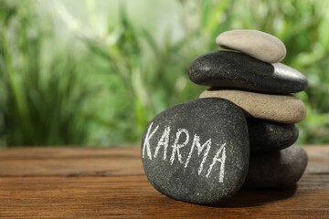 Stones with word Karma on wooden table, closeup. Space for text
