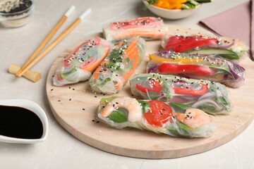 Delicious rolls wrapped in rice paper served on light table, closeup