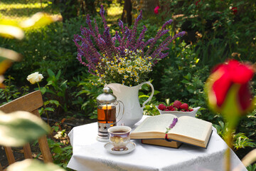 Beautiful bouquet of wildflowers and books on table served for tea drinking in garden