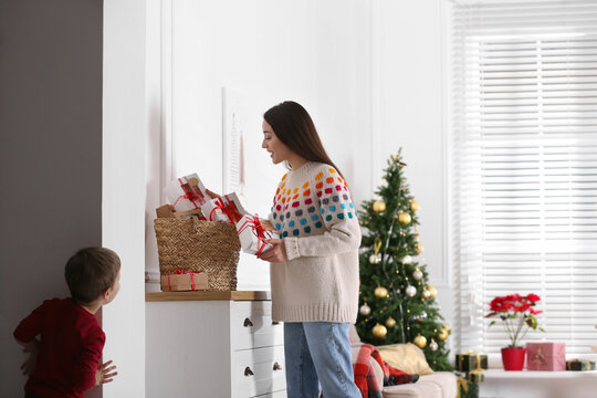 Little boy watching his mother taking gift from Advent calendar at home. Christmas tradition