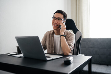 Middle aged asian man working at home with laptop.