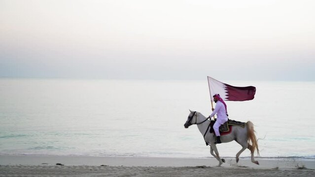 A knight riding a horse running and holding Qatar flag near the sea
