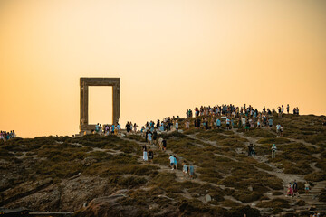 Portara of Naxos full of people at sunset - obrazy, fototapety, plakaty