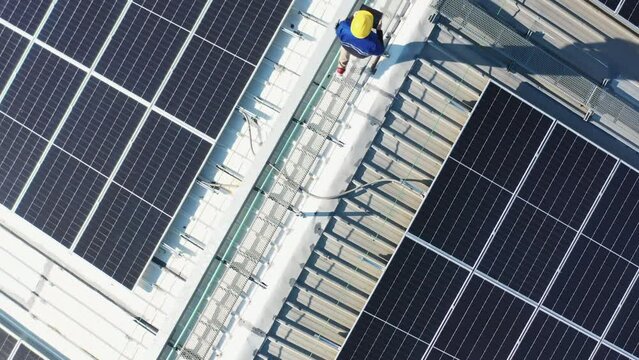 Aerial asian engineer service and checking solar cell on the toproof of factory. Worker technician inspection and repair solar cell panels. Green energy, ecology and alternative power concept