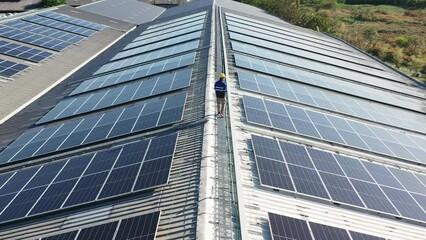 Aerial asian engineer service and checking solar cell on the toproof of factory. Worker technician inspection and repair solar cell panels. Green energy, ecology and alternative power concept