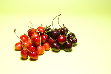 Ripe red and burgundy cherries in close-up on a yellow background.