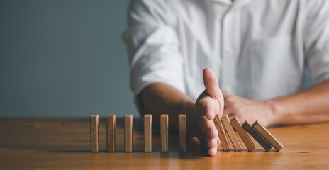 Risk and Strategy in Business, Hand stopping wooden block domino business crisis effect or risk...