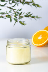 candle in a jar with the out-of-focus background of an orange.