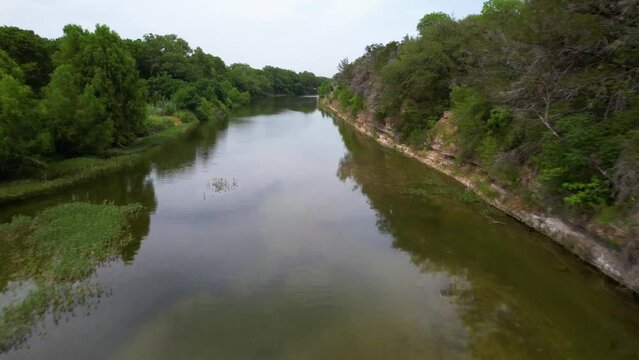 Aerial footage of the Blanco River in Blanco Texas in the Texas Hill Country. Fast flight straight along rock ledge
