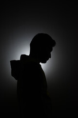 Cleanly define silhouette of man looking down wearing hood