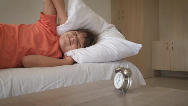 Dissatisfied child morning with alarm clock. A dissatisfied little girl try to get up with working alarm clock in the morning.