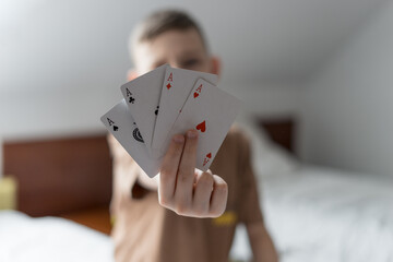 cheerful boy play game or closeup of playing cards in kid hand indoor