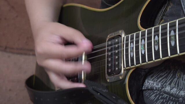 Pick mediator held in hand strikes the strings. Close-up of playing electric guitar. Musician holds a guitar in his hands and plays vigorously plays a solo. Rock guitar performance