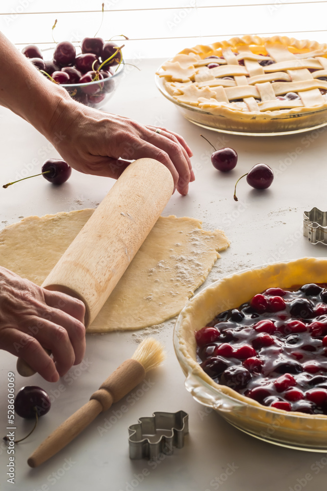 Wall mural hands using a rolling pin to roll out a pie shell to prepare a cherry pie.