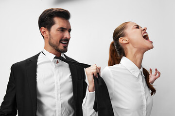 Man and woman pulling on tie anger business looking at each other screaming with hands up in white isolated background. The concept of business in a couple harassment startup copy space