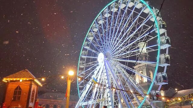 Kyiv, Ukraine, January 23, 2022-Panoramic Ferris wheel, in city during snowfall on winter night. Urban landscape. Christmas New Year background. Heavy snowfall at night in the city in winter