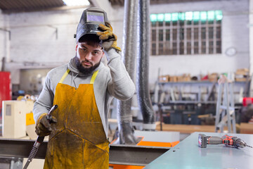 Young man using welder for construction work at the workshop