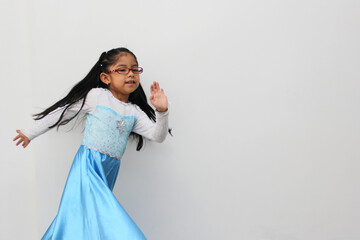 Poor 4-year-old Latin brunette girl is dressed as a happy princess with her costume to go to a children's party and feel strong and empowered