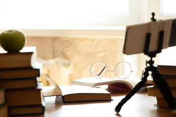 Books on the table next to glasses and a mobile phone on stands in the apartment ,online learning ,distance learning ,education