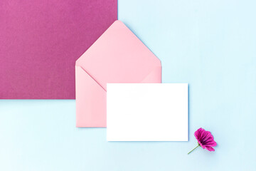 White blank card, pink envelope and flowers . Top view Flat lay Mockup