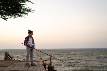 Boy fishing on the lake at sunset. Child fishing spinner rod in summer.