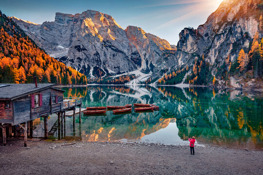 Tourist takes photo of Braies (Pragser Wildsee) lake with boats and fishing dock. Majestic summer scene of Fanes-Sennes-Braies national park, Dolomite Alps, South Tyrol, Italy, Europe.