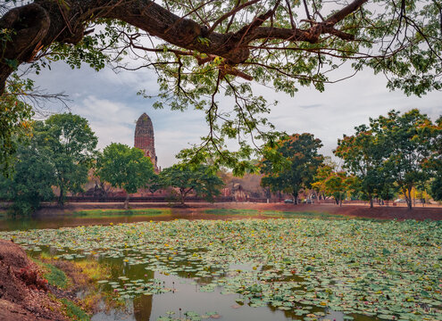 Misty summer view of ruins of the ancient Buddhist temple Wat Phra Ram. Stunning morning scene of small pond with yellow water lilies, Ayutthaya, Thailand, Asia. Traveling concept background.