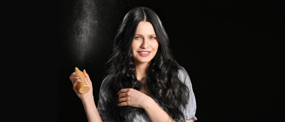 Beautiful young woman with hair spray on dark background