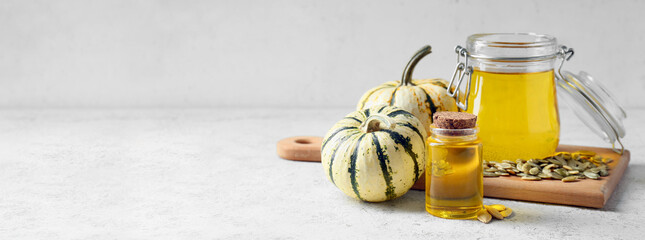 Bottle and jar with pumpkin seed oil on light background with space for text