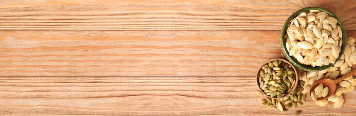 Bowls of natural pumpkin seeds on wooden background with space for text