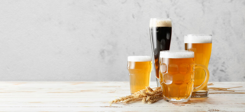 Glassware with fresh beer on light background with space for text
