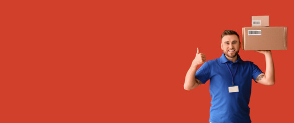 Handsome delivery man with parcels showing thumb-up on red background with space for text