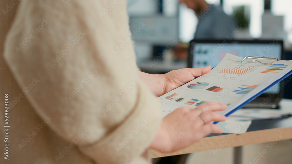 Poster closeup of woman hands holding clipboard with papers looking at pie chart and business profit data i