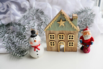 christmas card. Christmas tree, a small house and a figurine of Santa Claus	