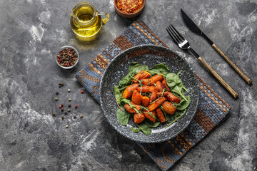 Composition with plate of tasty baked carrots and spices on grunge background