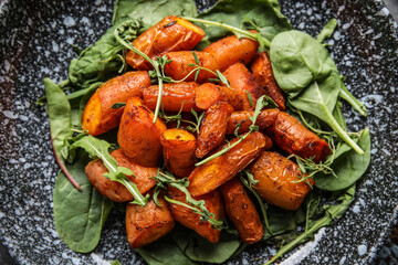 Plate of tasty baked carrots with greens, closeup