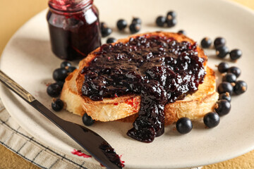 Plate with tasty toast and black currant on beige background, closeup