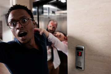 Frightened man running from evil zombies, trying to escape elevator from terrifying scary walkers....