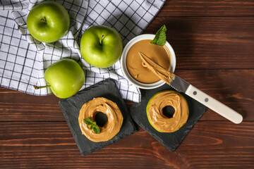 Tasty apple rounds with nut butter on wooden table