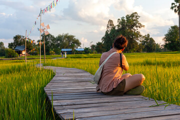 Behind the scenes, a female photographer sits on a wooden bridge between the fields to photograph the sights.