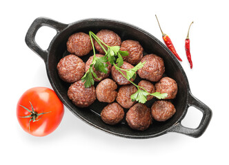 Baking dish with tasty meat balls, parsley, tomato and chili peppers on white background