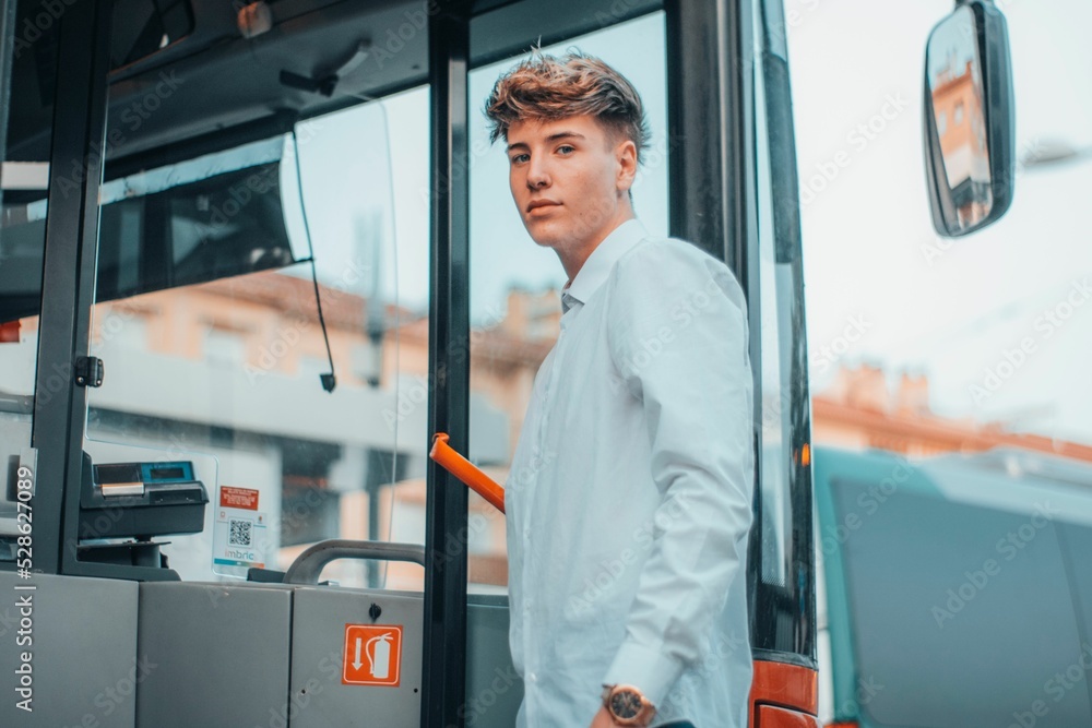 Wall mural Cool young Spanish male riding up a bus while looking at the camera